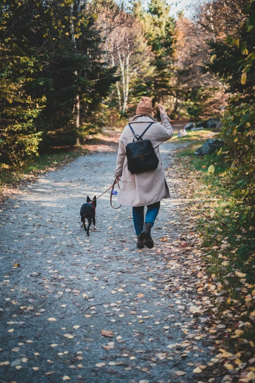 the woman in the coat is walking her dog