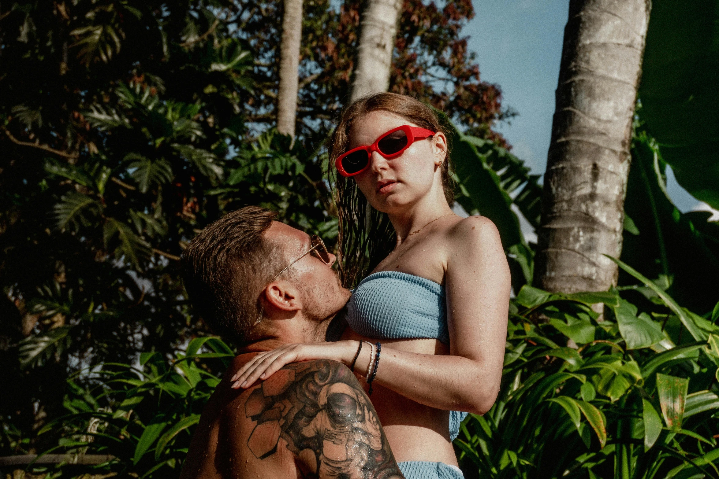 a man in red glasses hugging a young woman with a bushy area behind him