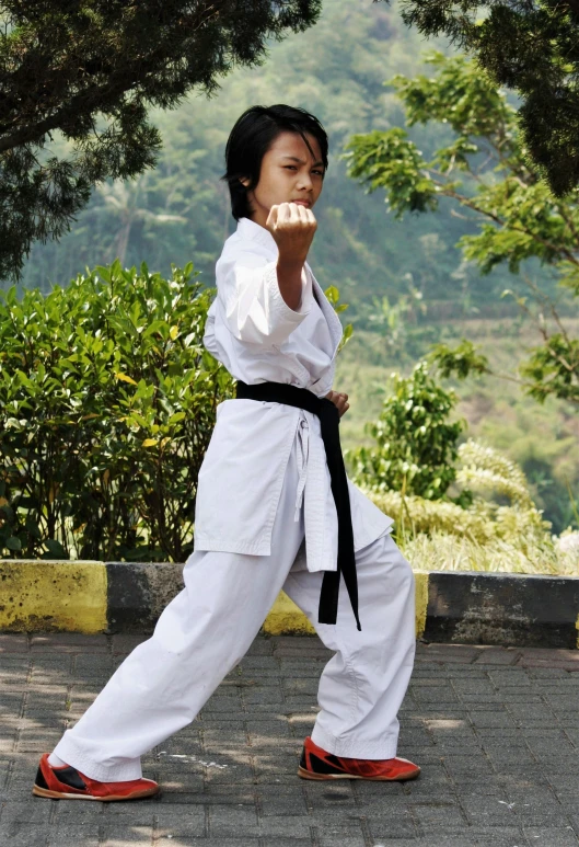 a young person dressed in karate attire in a park
