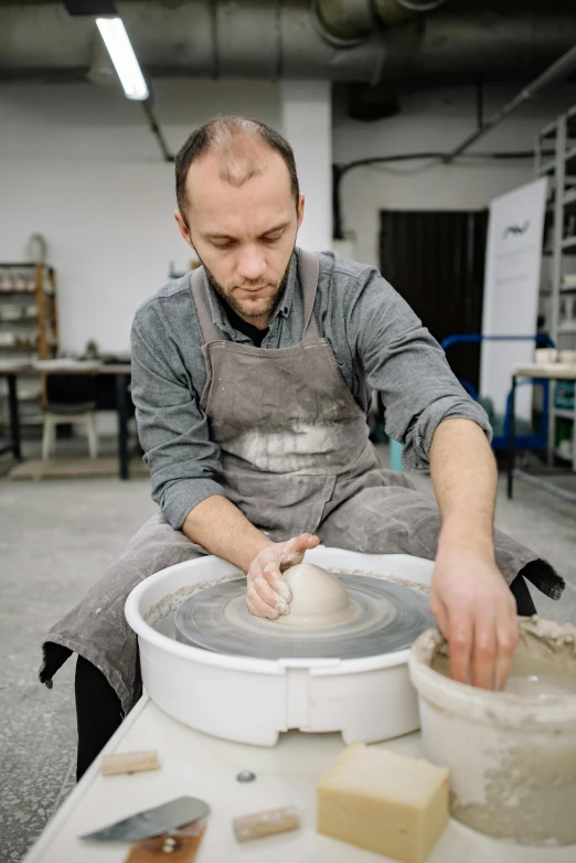 a man using a spinning wheel in a pottery workshop