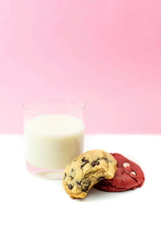 two cookies on the table next to a glass of milk