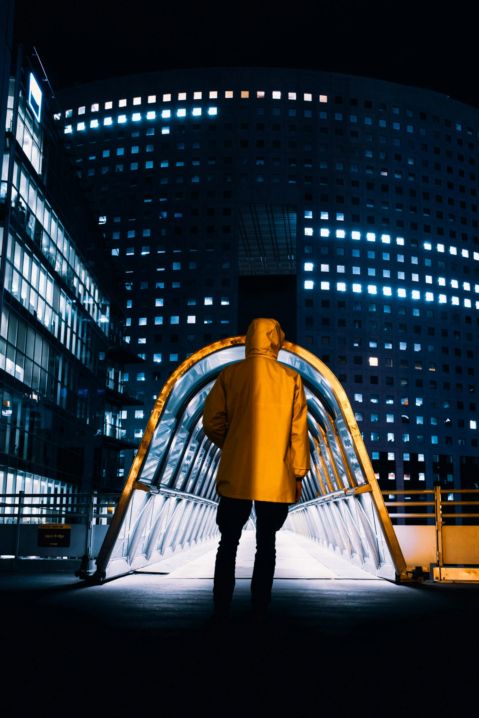 a man stands alone near a building in the nighttime