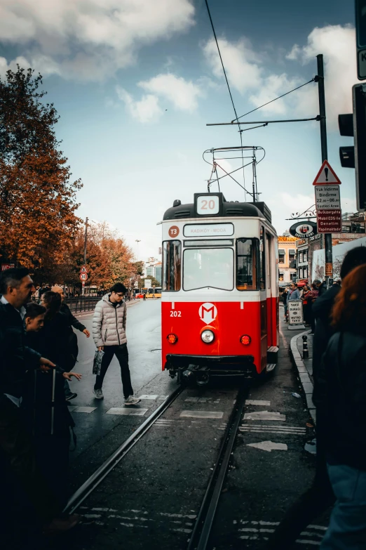 a red and white cable car traveling down tracks