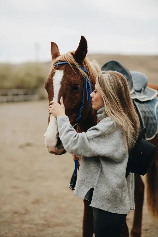 two women are petting a brown horse