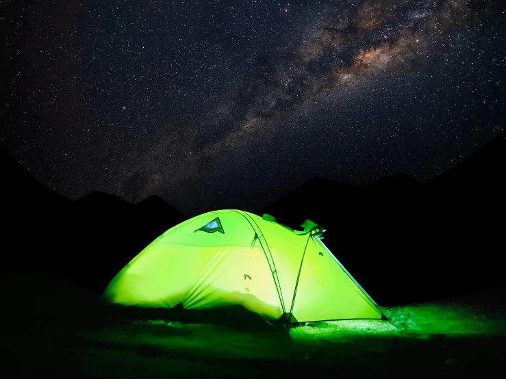 a tent sits on the ground under a starr filled sky
