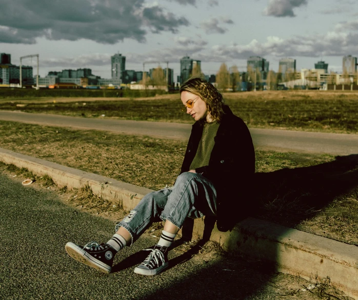 a young man is sitting on the side of a building looking off into the distance