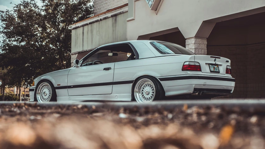 white bmw coupe parked in front of a house