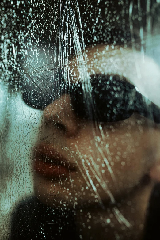 a woman wearing sunglasses while standing in front of a window