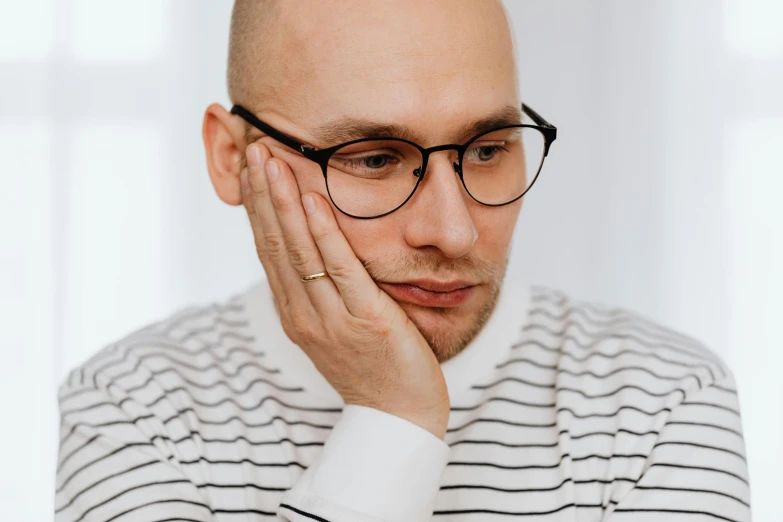 man with eyeglasses posing for camera next to white curtain