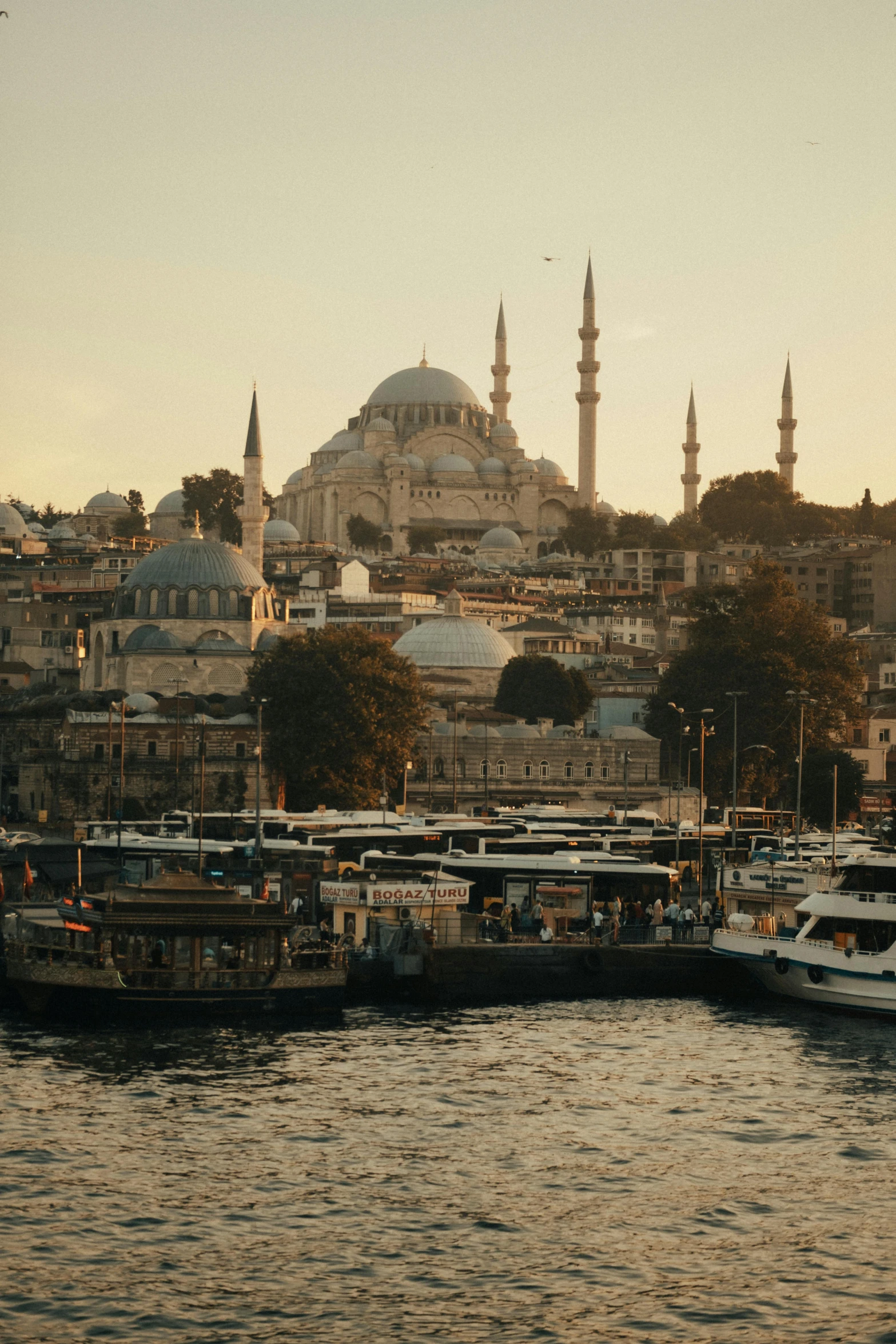 several boats on the water in front of an island with a mosque on the hill in the background