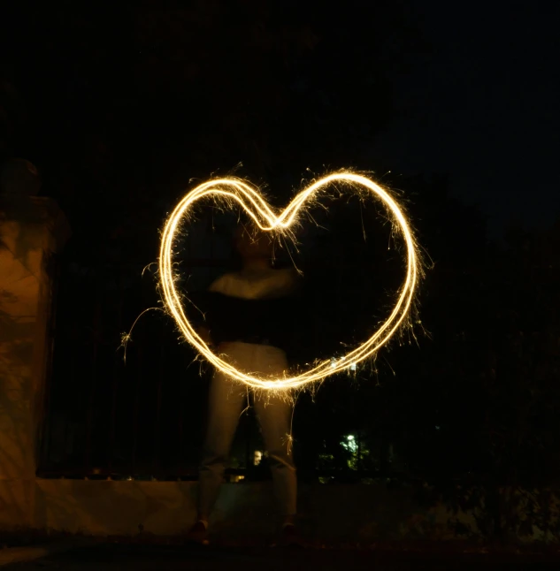 a person standing with their back facing the camera, making a heart shape with the sparkle