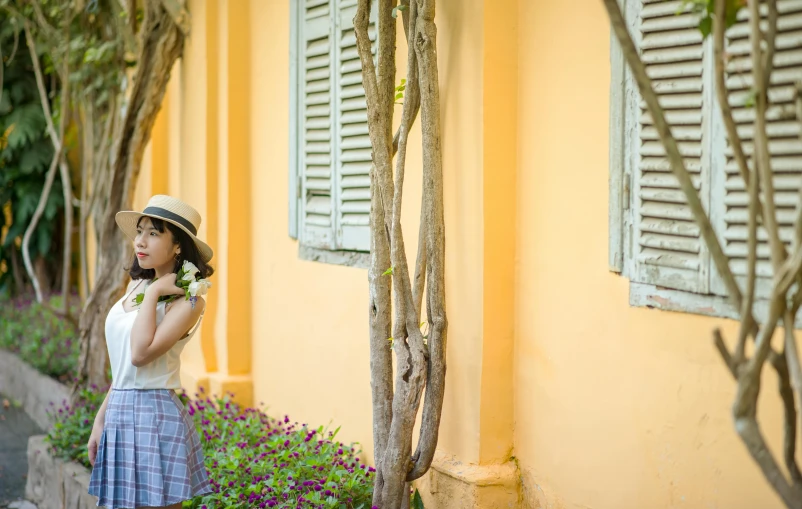 a pretty young lady standing in front of a yellow building