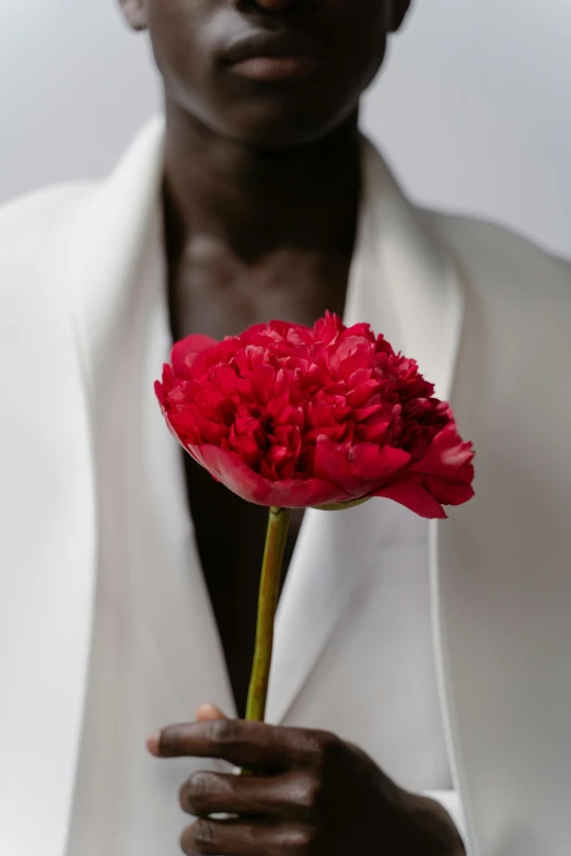 a man holds a red flower in his hand