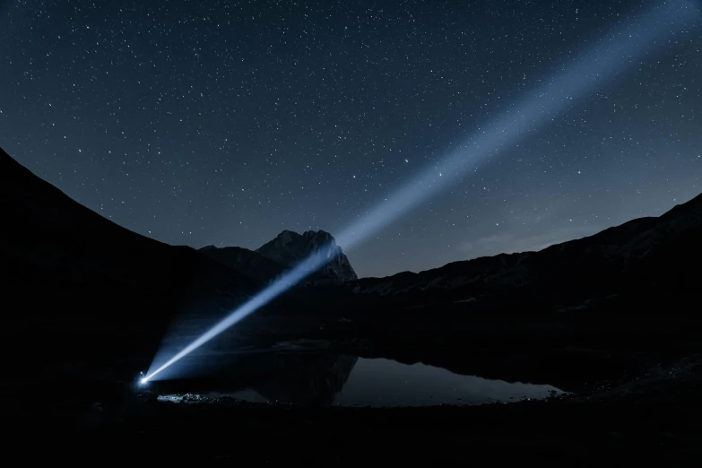 stars shine behind two mountains as a mountain lake sits below