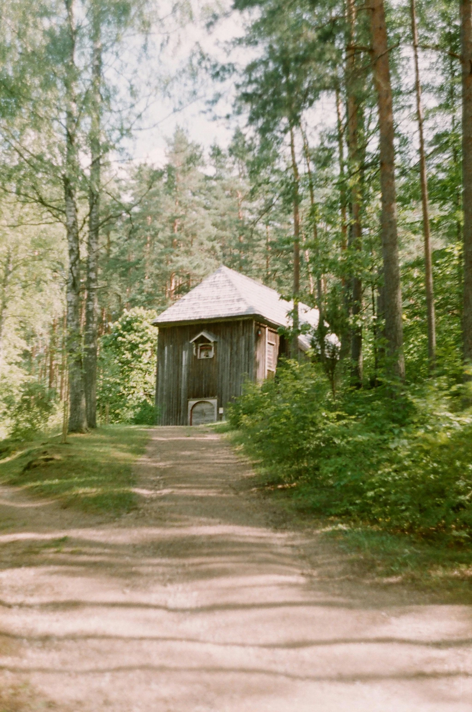 the dirt road has a barn in the background