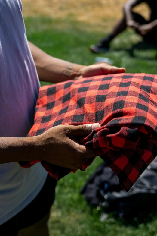 a person is holding an orange and black blanket