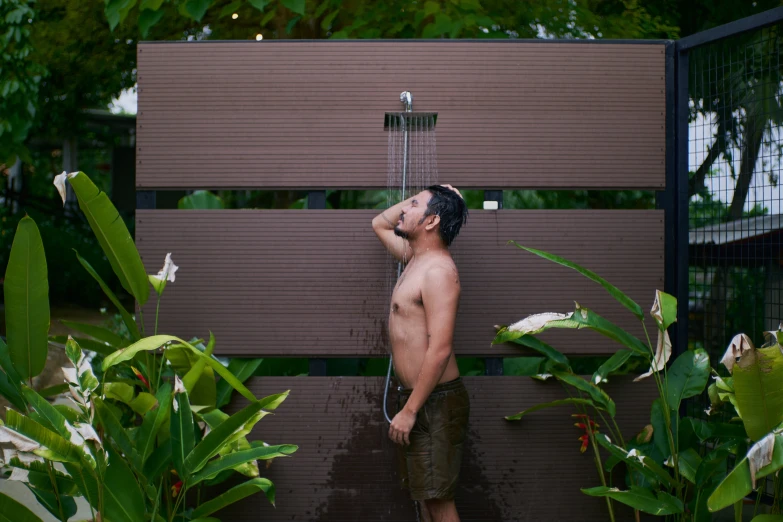 a shirtless man washing his face outside