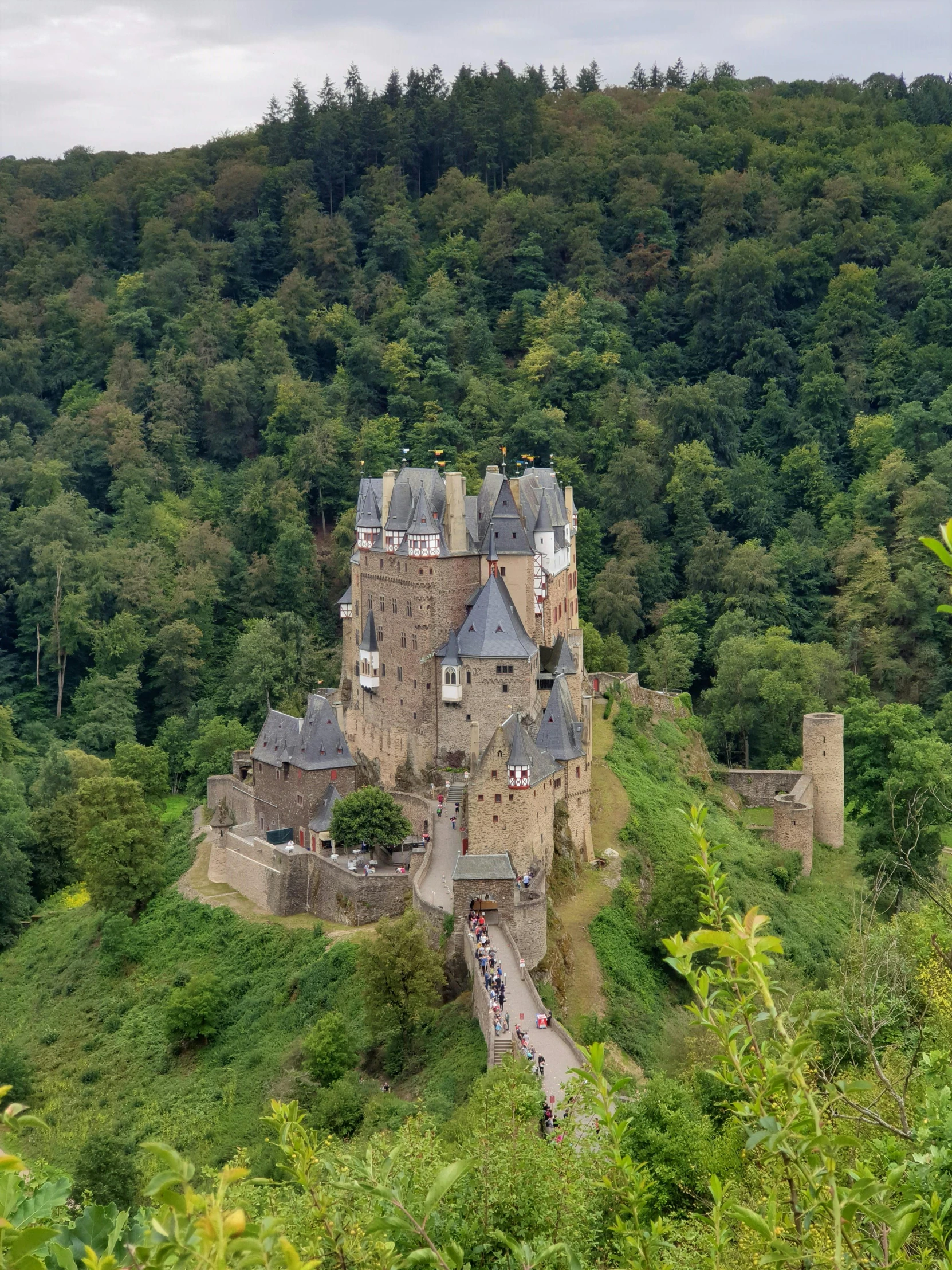 an old castle perched atop the side of a lush green hillside