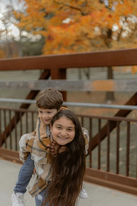 a little boy riding on the back of a girl