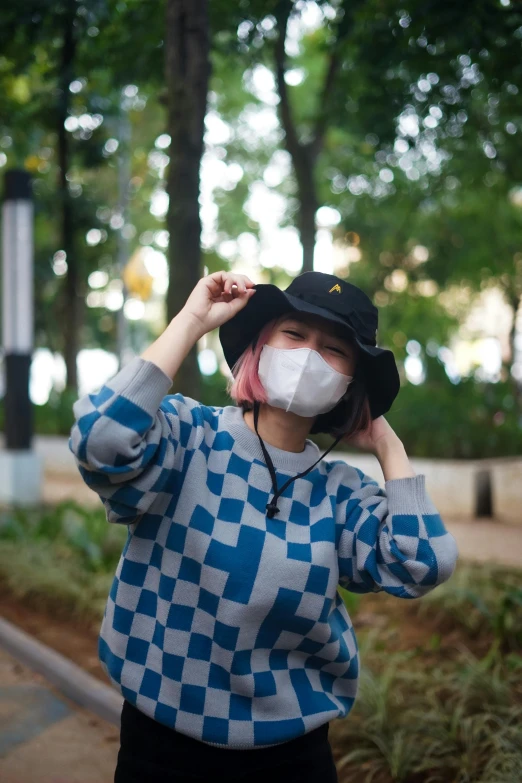 an asian woman wearing a face mask holds up her mouth to protect it from the sun
