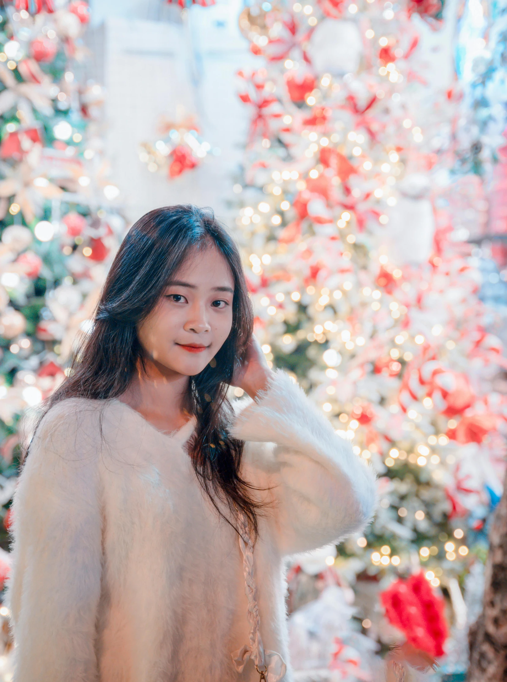 a woman holding her ear while standing next to a christmas tree