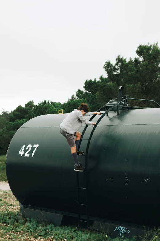 a man climbing down an object that looks like a tank