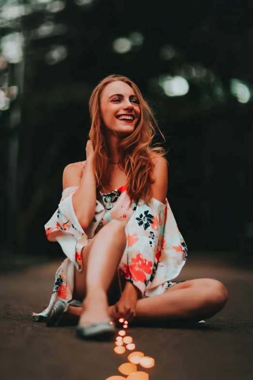 a beautiful woman in a floral dress sitting on the ground