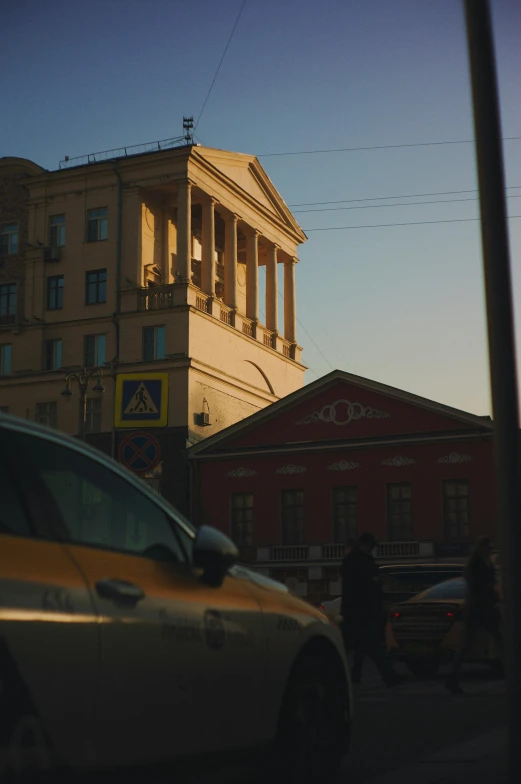 two cars and a car stopped at a stop sign in front of a building with an arch