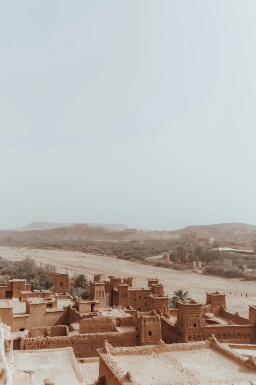 an adobe village in the desert surrounded by sand and trees