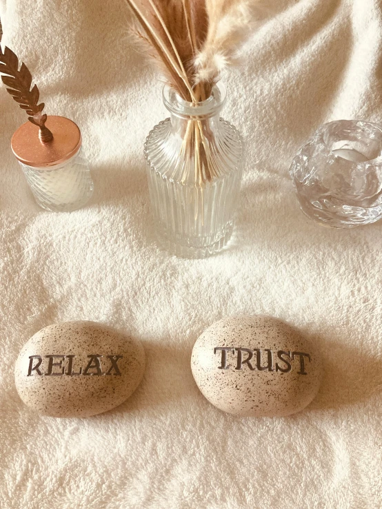 three rocks with writing sit on a white bed