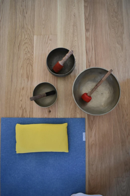 a blue rug on a wooden floor, two metal bowls and one yellow object