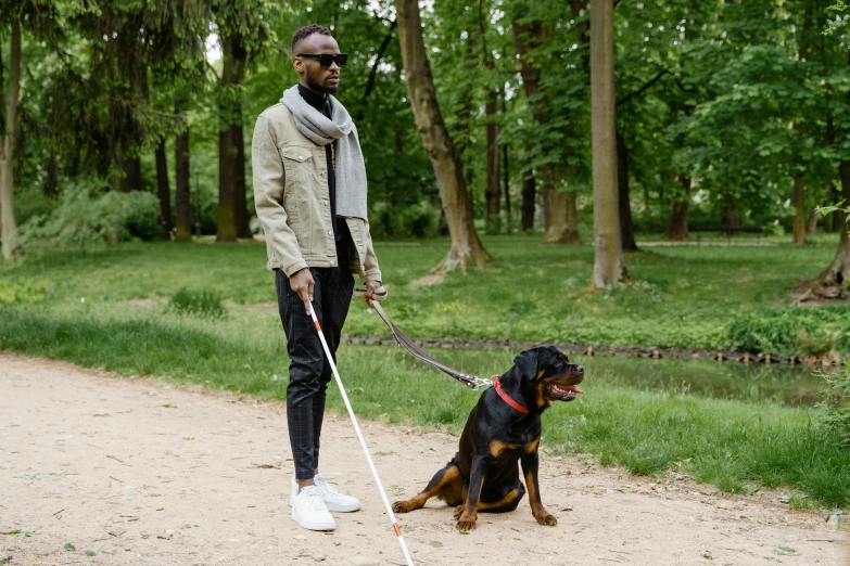 a person standing on the road with a black and brown dog on a leash