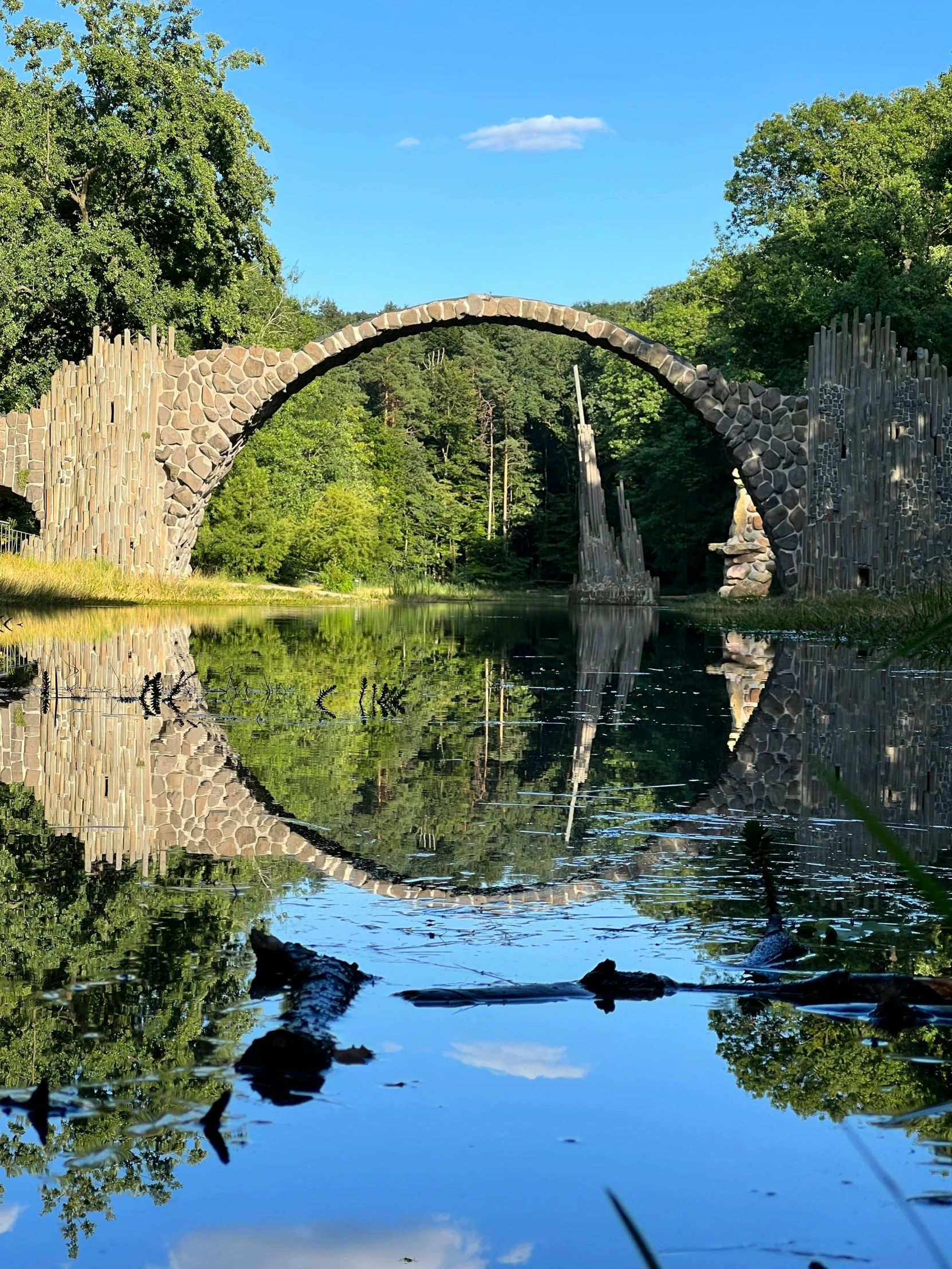 an old stone bridge is surrounded by the trees