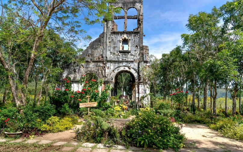 a very old building surrounded by trees and flowers