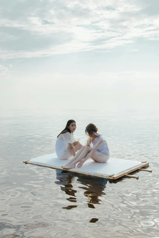 two women sitting on a floating object in the water