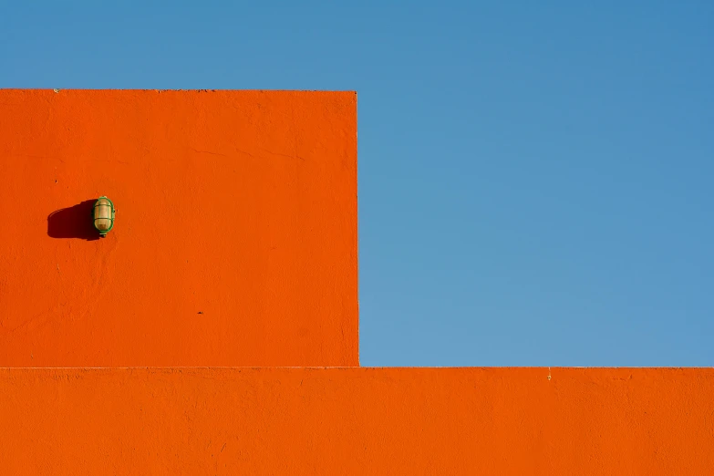 a street light attached to the side of a orange wall