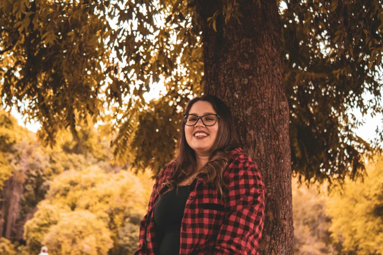 a woman standing next to a tree smiling