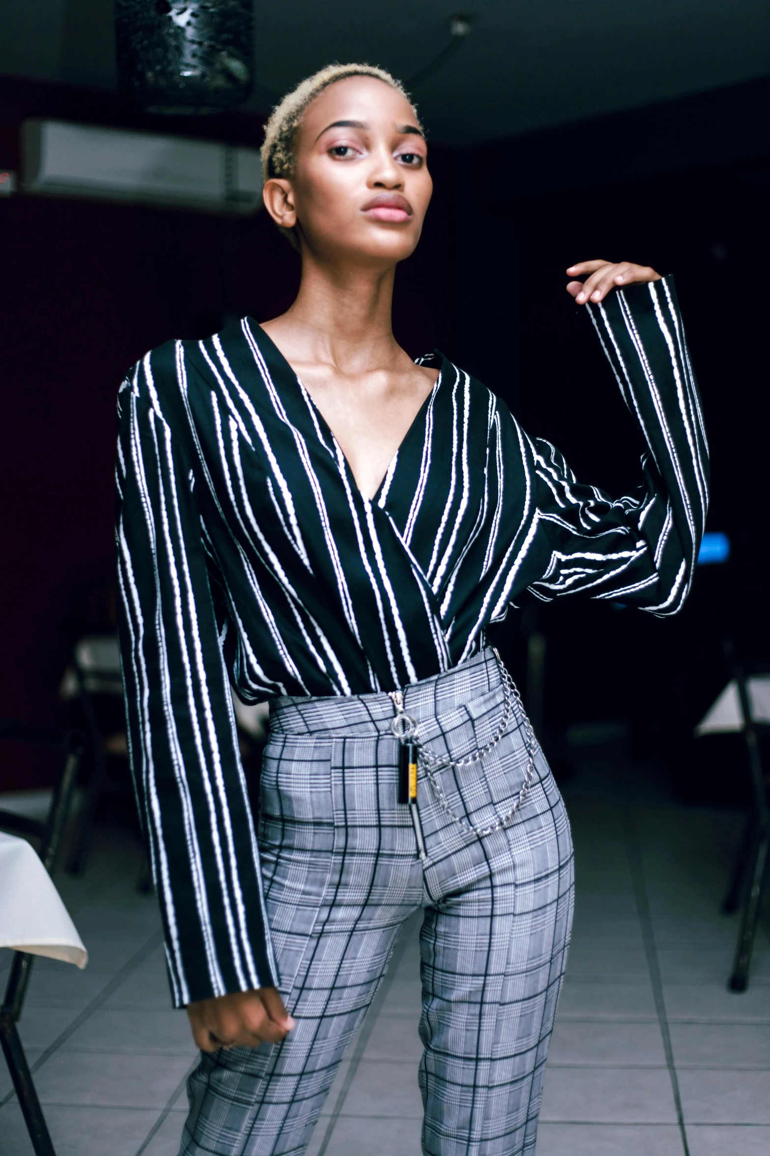 a beautiful young woman in striped clothes standing by a table