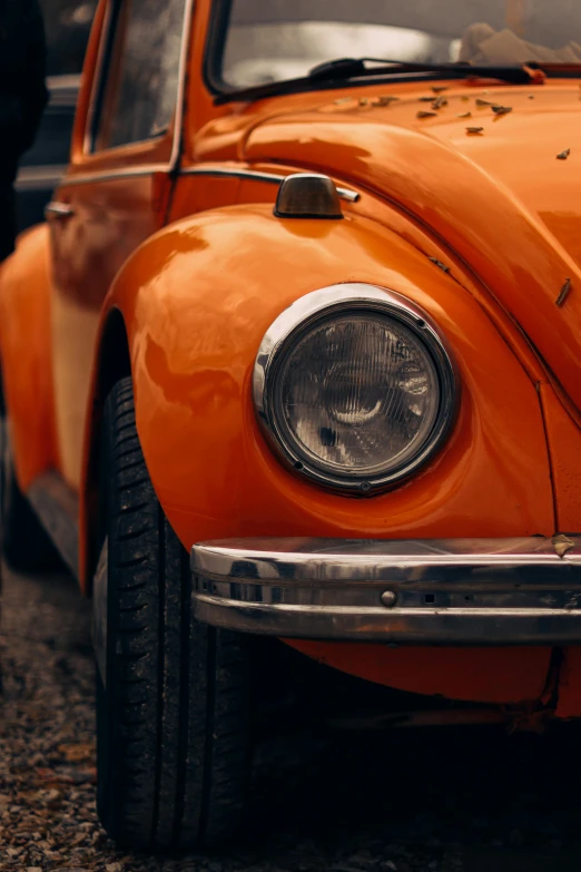 an orange vw bug is sitting with its headlights turned