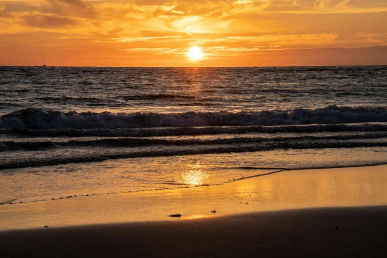 a beach with water and waves at sunset