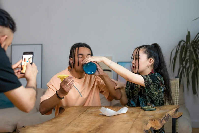 three people seated together and one person drinking out of a mug