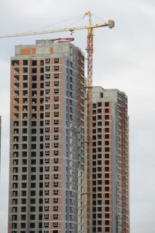 two tall buildings next to each other under a crane