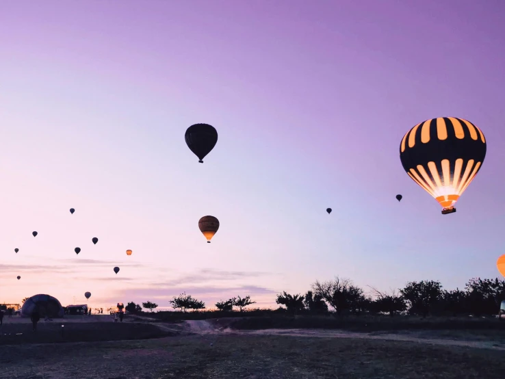 several  air balloons in the sky above a dirt road