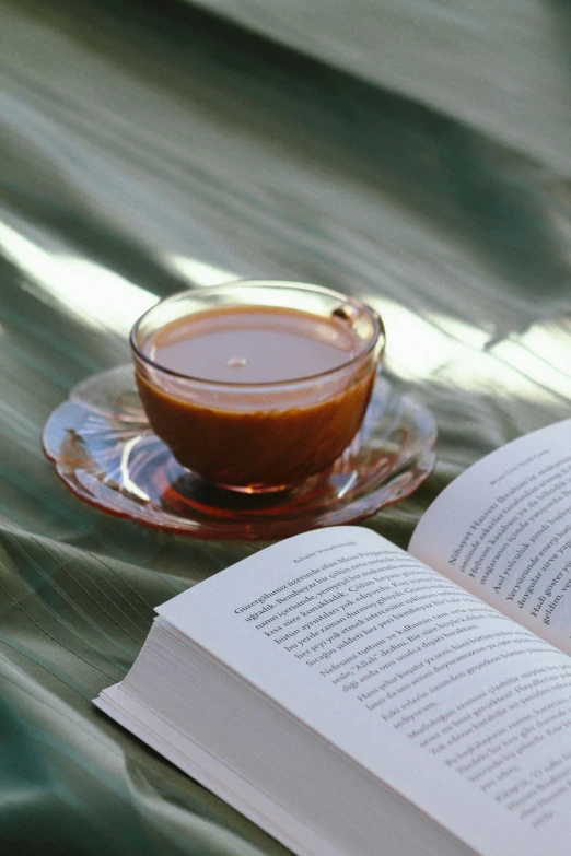 an open book and cup of liquid on a plate