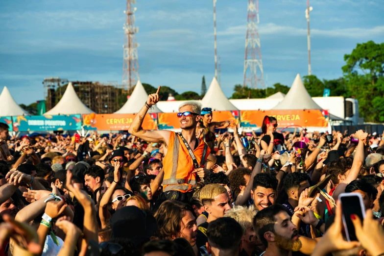 a crowd at an outdoor concert taking pictures and waving