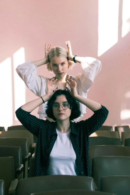 two women sit in chairs, one with her hair blown