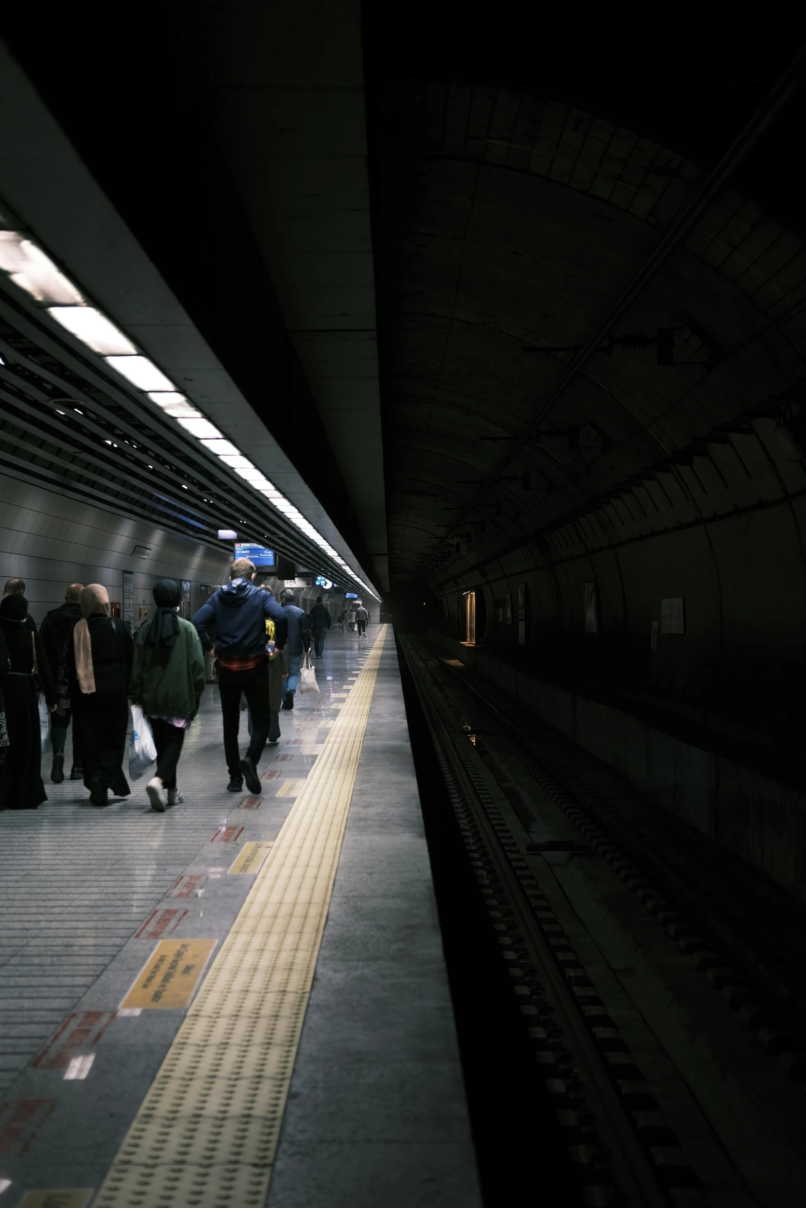 people are waiting on the side of a train station