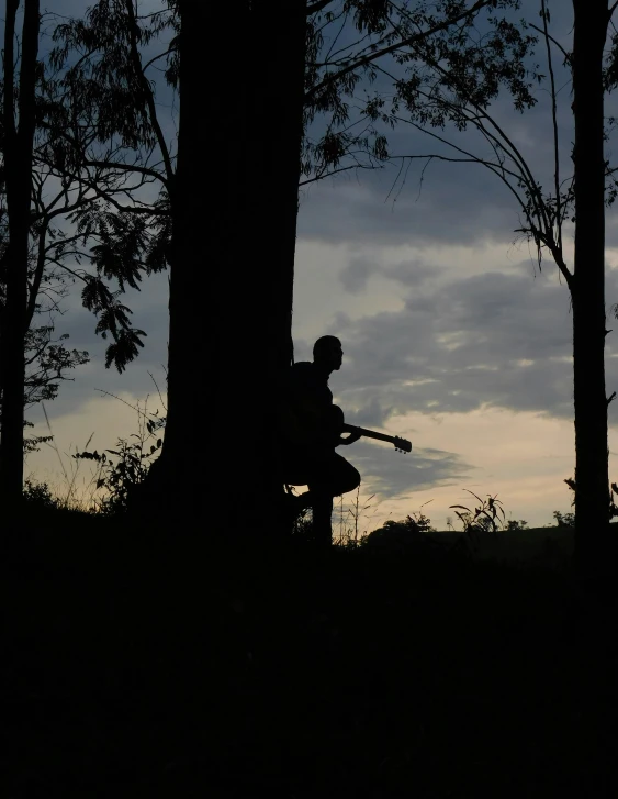 a silhouetted man sitting on a tree