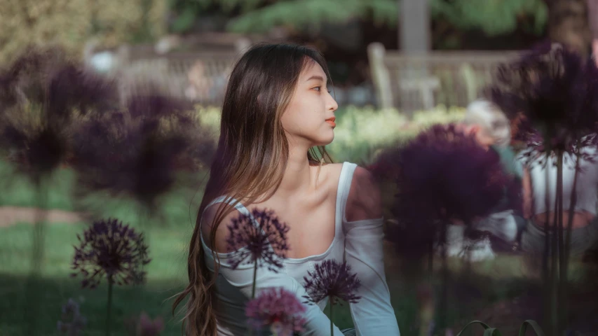 young female sitting in purple flowers near grass