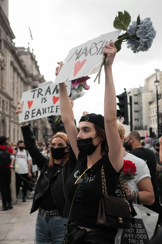 two women hold signs reading racism, iraq is real and a face mask